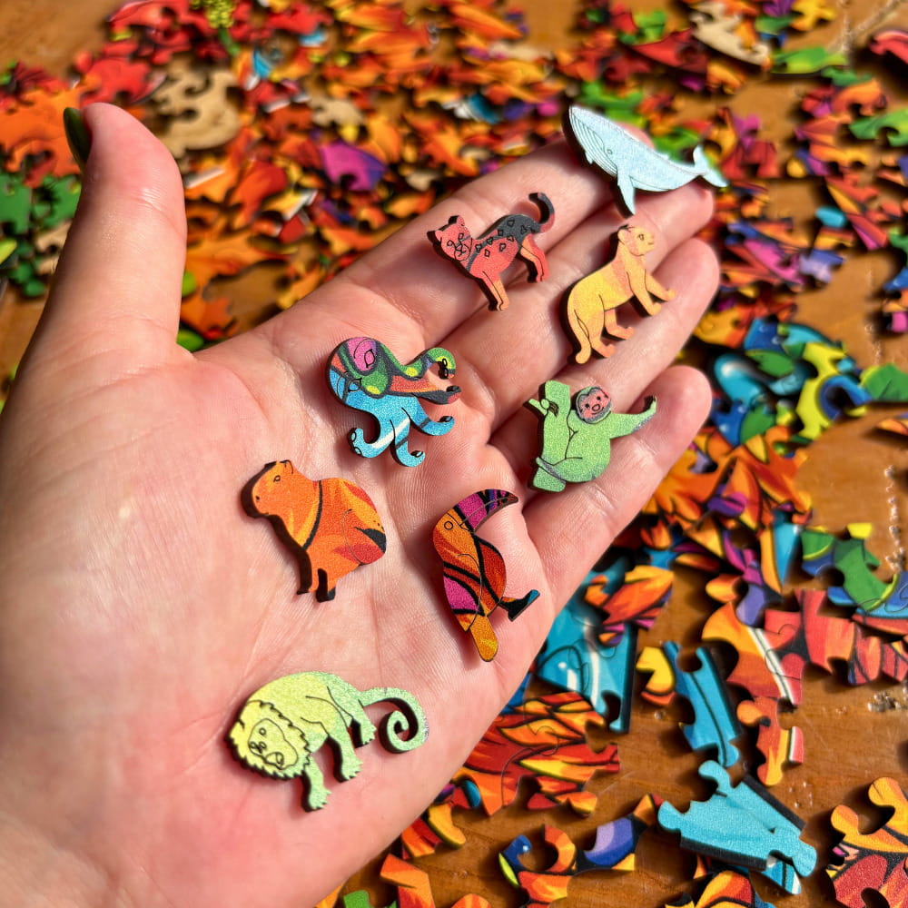 Palma da mão com diversas peças de quebra-cabeça em formatos de baleia, macaco, polvo e pássaros.