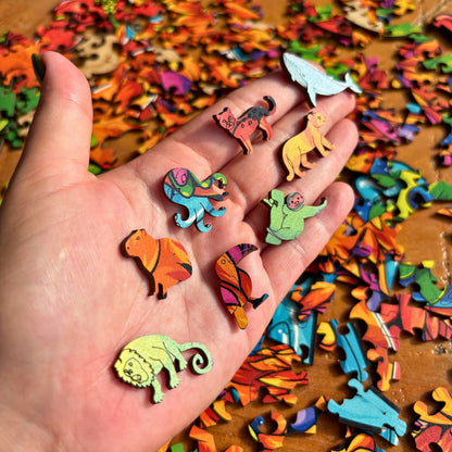 Palma da mão com diversas peças de quebra-cabeça em formatos de baleia, macaco, polvo e pássaros.