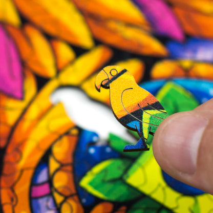 Mão segurando uma peça em formato de pássaro colorido prestes a ser encaixada no quebra-cabeça de madeira Puzi.