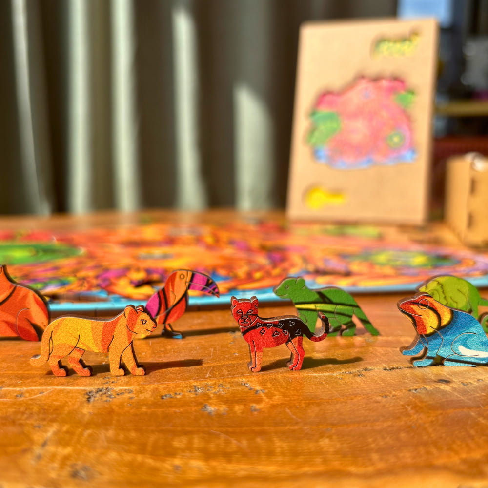 Peças de madeira em pé representando onça, tucano e sapo com pintura vibrante.