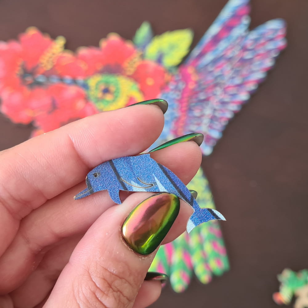 Mão segurando peça de quebra-cabeça de madeira em formato de boto.