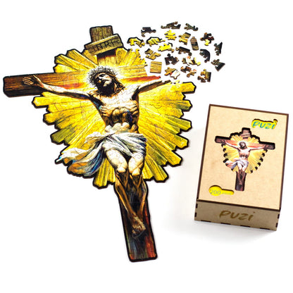 O quebra-cabeça Jesus Crucificado com algumas peças soltas ao lado da embalagem premium de madeira