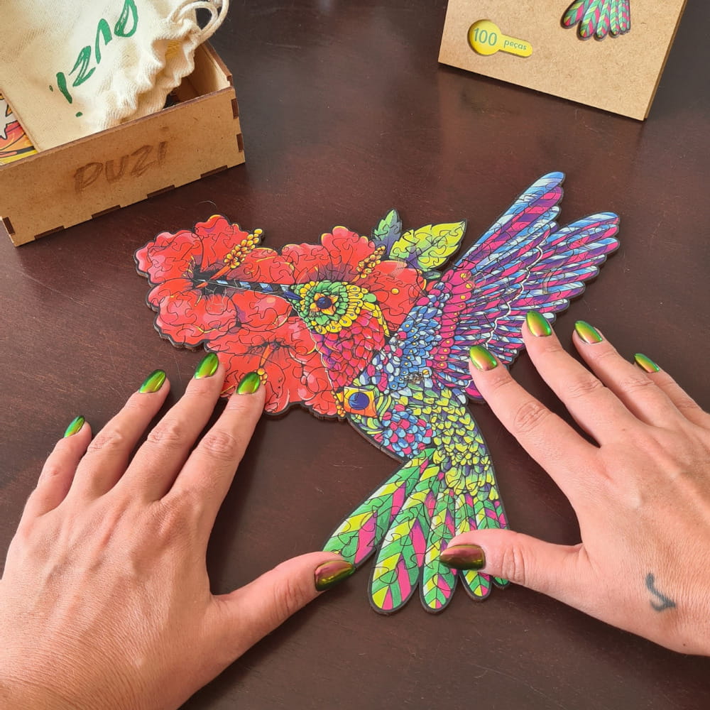 Quebra-cabeça de madeira montado em formato de beija-flor colorido sobre mesa escura.